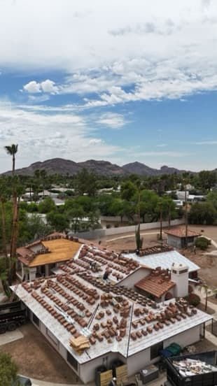 Tile roof mid-job with the old tile stripped, new underlayment across the deck, and concrete tile bundles staged for reset in Scottsdale, AZ